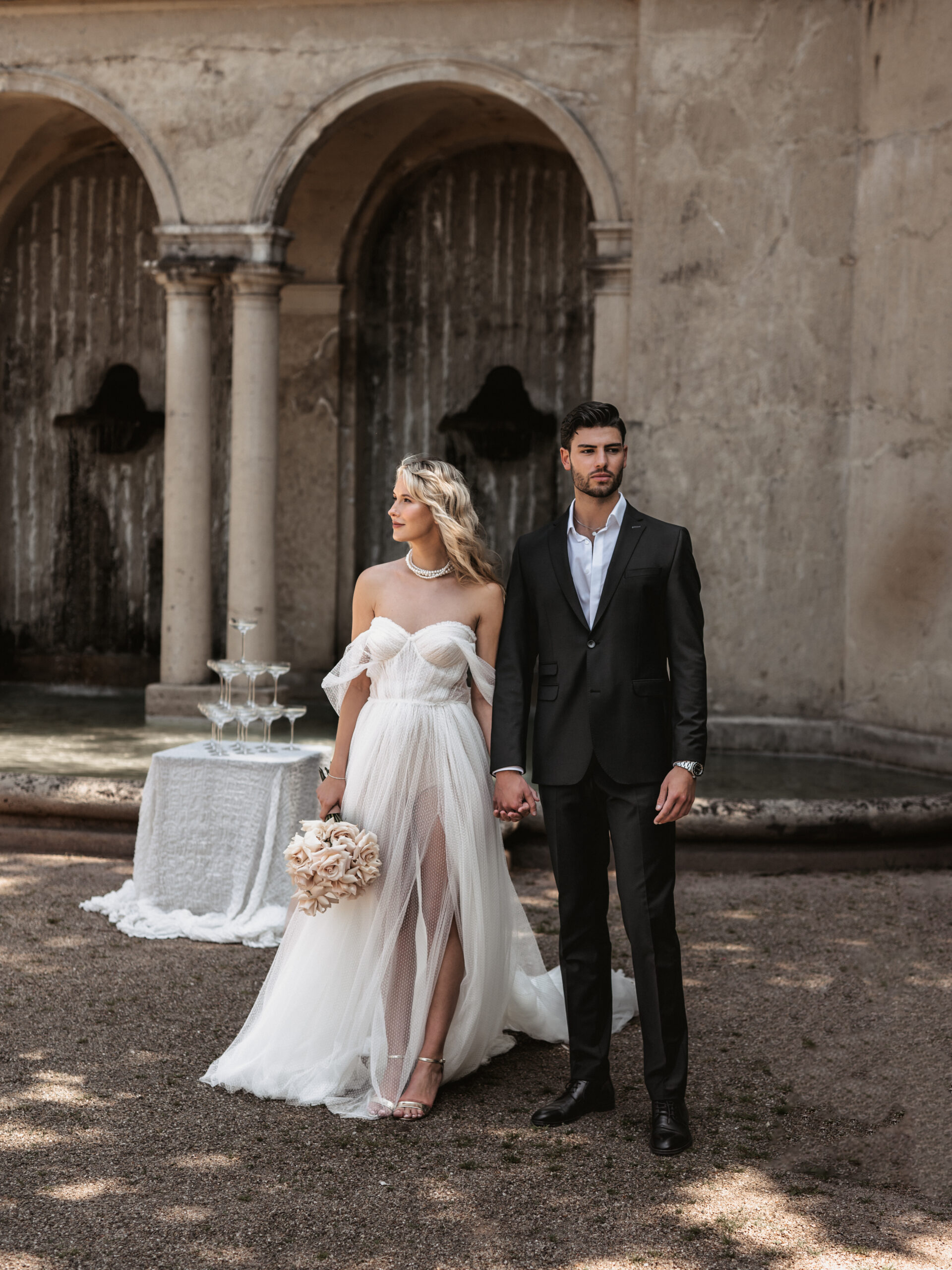 Elegantes Brautpaar vor historischen Steinbögen