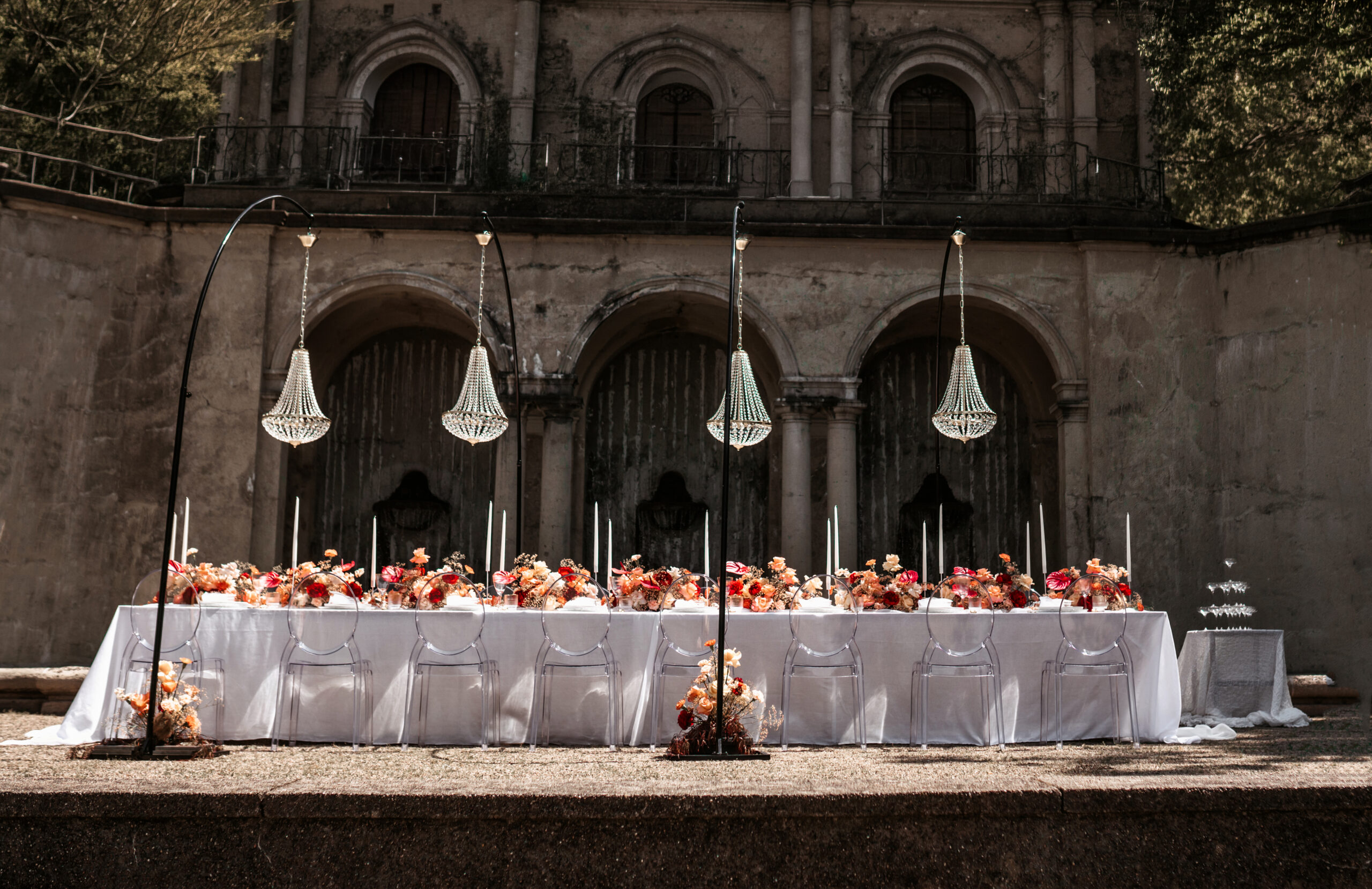 Festlich gedeckte Hochzeitstafel mit Blumen und Kronleuchtern im Innenhof – Hochzeitsfotografie von Kenan Egin