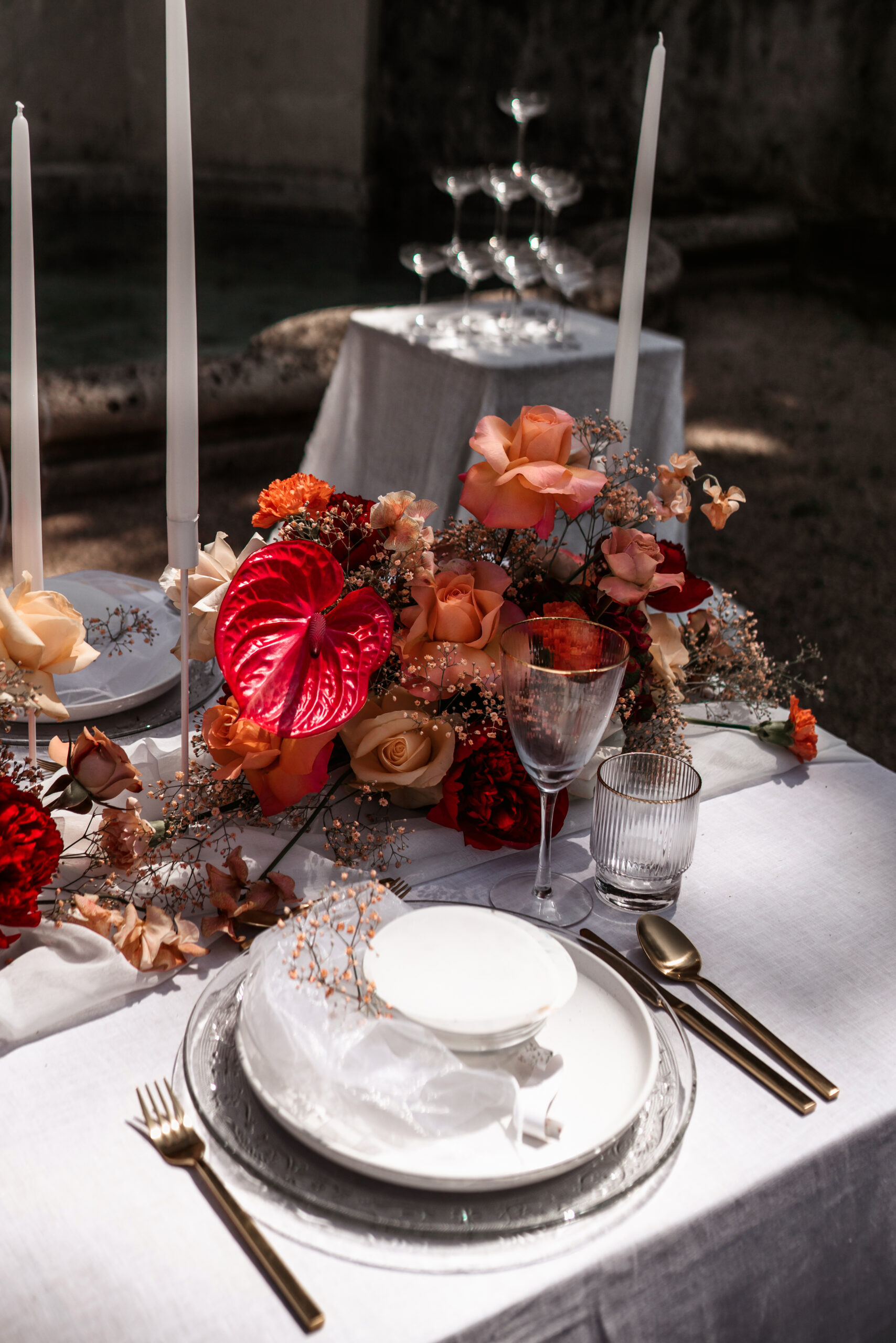 Hochzeitstisch mit orangefarbenen Rosen, roter Anthurie, weißen Kerzen und Gläsern – Hochzeitsfotografie von Kenan Egin