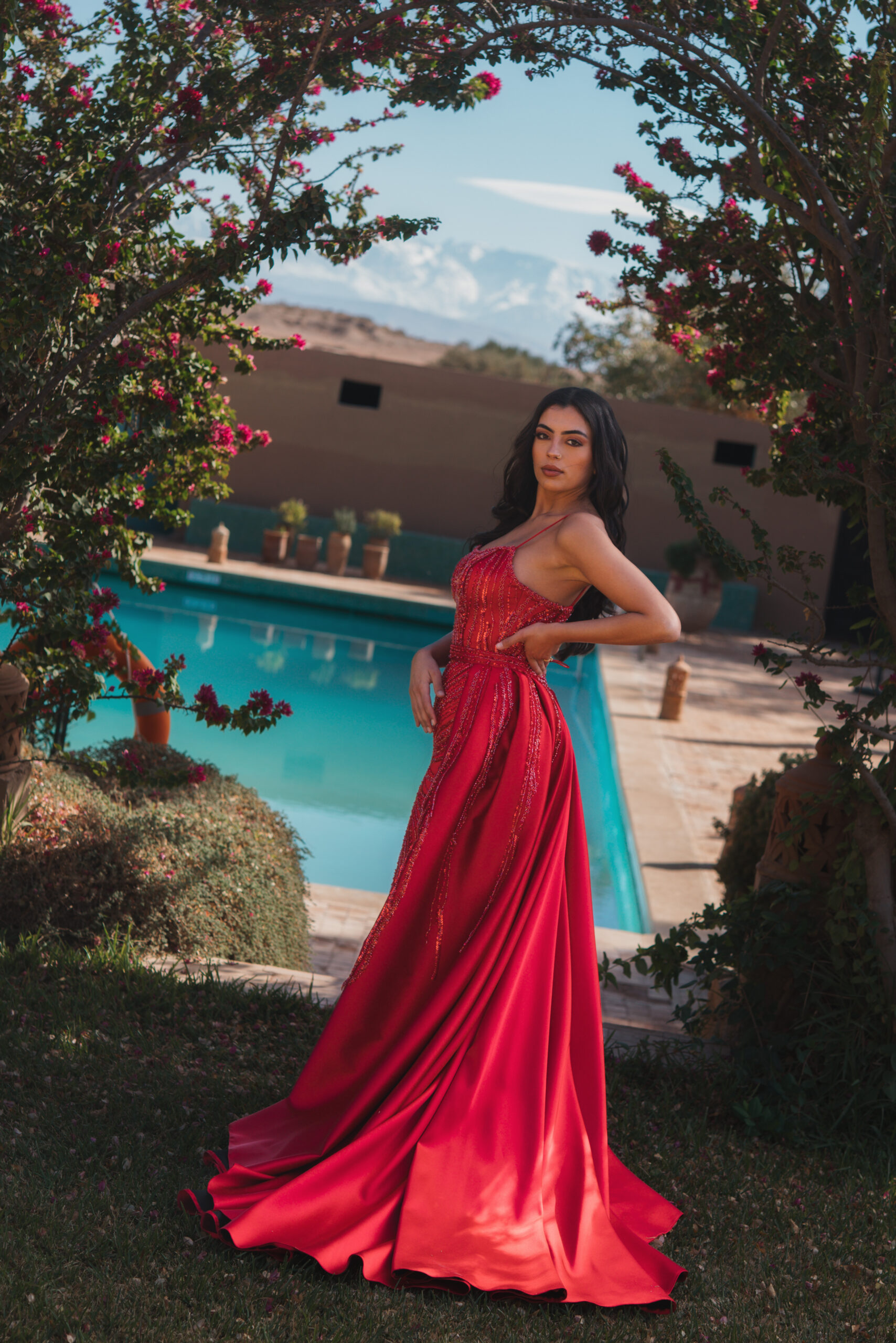 Frau im roten Abendkleid am Pool in Marakesch.